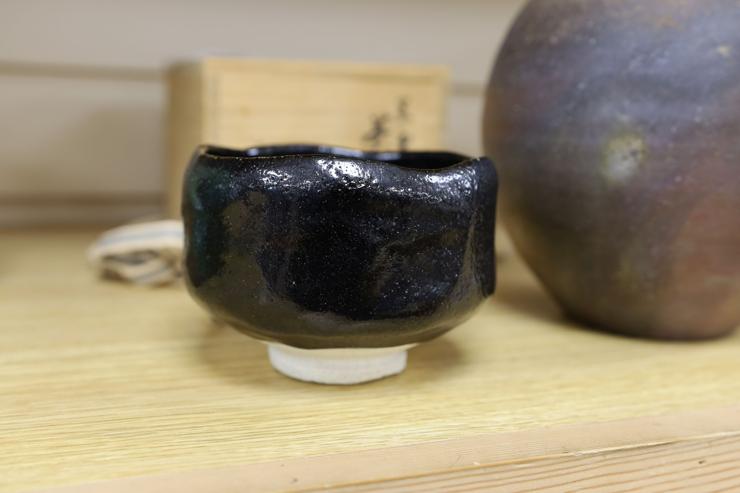 Japanese studio pottery: a boxed black glaze stoneware unomi tea bowl, with impressed mark, together with a ovoid vase, marked, 21cm tall
